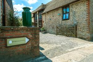 a building with a green trash can on a brick wall at Berehayes Cottages in Whitchurch Canonicorum