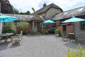 a patio with tables and umbrellas in front of a building at Berehayes Cottages in Whitchurch Canonicorum +10 photos