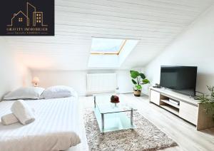 a white bedroom with a large bed and a television at Le Chaleureux in Marignier