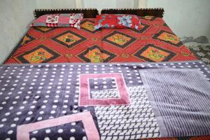a bed with a comforter with the letter k on it at श्री बांकेबिहारी सेवाधाम in Vrindāvan +7 photos