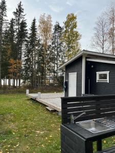 a black building with a sink and a dock at A simple stuga on a lake incinerating toilet in a separate building next to the cabin Water for drinking and washing hands dishes comes from two containers that attach to a faucet through a simple electric pump OBS no shower on site in Grythyttan +4 photos