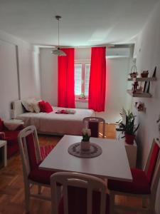a room with a bed and a table and red curtains at Apartman Mira in Požarevac
