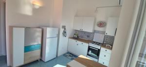 a kitchen with white cabinets and a refrigerator at La casa sotto le stelle - Ustica in Ustica +9 photos