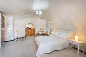 a bedroom with a white bed and a table at Spilies by Thireas in Vourvoúlos