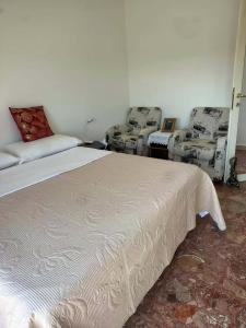 a bedroom with a bed and two chairs in it at stazione Lina house in Venice