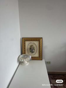 a white wall with a picture and a vase at stazione Lina house in Venice