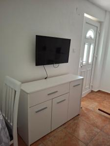 een witte kast met een flatscreen-tv aan de muur bij Anastasija in Merdari +1 foto