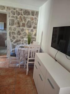 een eetkamer met een tafel, stoelen en een tv bij Anastasija in Merdari
