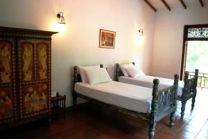 a bedroom with two beds and a wooden cabinet at Okvin River Villa in Bentota