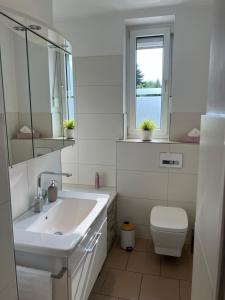 ein Badezimmer mit Waschbecken und Toilette und einem Fenster in der Unterkunft Ruhrperle Apartment 1 Essen in Essen + 7 Fotos