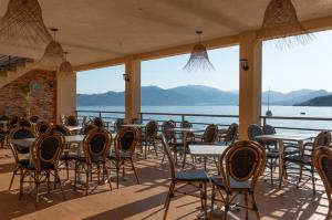 a restaurant with tables and chairs with a view of the water at HOTEL CAMPOMORO in Belvédère-Campomoro