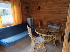 a living room with a couch and a table and chairs at Domki Sosnowa dolina We wielu in Wiele