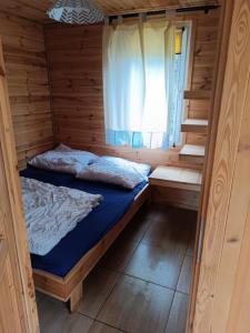 a small room with a bed in a wooden cabin at Domki Sosnowa dolina We wielu in Wiele
