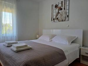 a white bedroom with a bed with towels on it at Apartments Sandra in Turanj