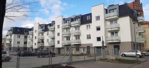 a large white building with cars parked in a parking lot at Apart 36 in Lębork