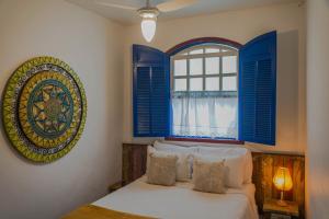 Schlafzimmer mit einem Bett und einem Fenster mit blauen Rollläden in der Unterkunft Pousada Travessias in Tiradentes + 58 Fotos