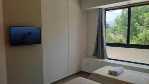 a room with a tv on the wall and a window at Olmos Suites in Mina Clavero
