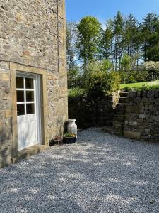 a stone building with a door and a stone wall at Luxurious Granny House Bell Busk in Malhamdale in Skipton