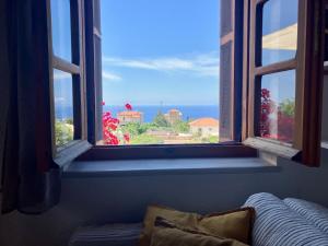 a window with a view of the ocean from a couch at Bright Cozy Home with Terrace, Garden & Sea View in Neokhórion