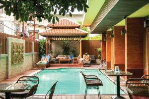 a swimming pool with chairs and people sitting around it at Lamphu Tree House Boutique Hotel in Bangkok