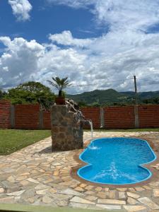 a swimming pool with a water fountain in a yard at Chácara Recanto Ribeiro in Pirenópolis
