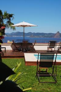 a patio with chairs and an umbrella and a pool at Gerthrudes Bed & Breakfast in Rio de Janeiro
