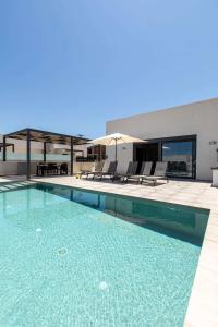a swimming pool with chairs and a building at Sage Villa by Vintage Travel in Tavronitis
