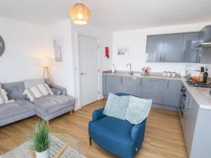 a living room with a blue chair and a kitchen at Glenholme Apartment 6 in Redcar +18 photos
