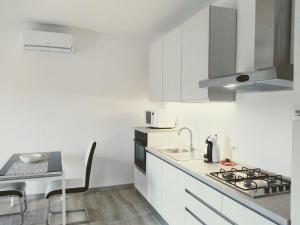 a white kitchen with a sink and a stove at Guest House - La bella vita in Orosei