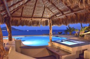 a swimming pool with a straw umbrella and the ocean at Villa Marlin by Cabo Villas in La Paz +19 photos