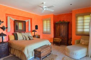 a bedroom with orange walls and a bed and a chair at Villa Marlin by Cabo Villas in La Paz