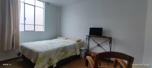 Un dormitorio con una cama y una silla y una ventana. en Posada Estela, en Lima