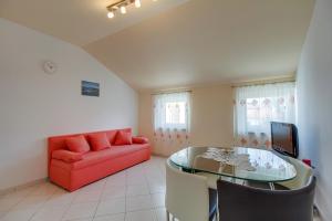 a living room with a red couch and a glass table at Apartment Jasna Near Čikat Bay and Center with Private Parking in Mali Lošinj