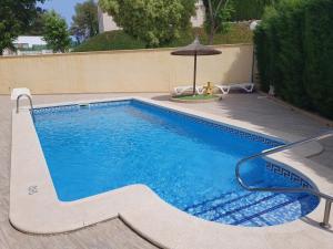 una piscina con una sombrilla al lado de una piscina en Casa la Fana, en Orihuela Costa
