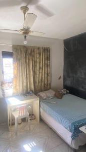 a bedroom with a bed and a table and a ceiling at Apartamento no centro in Jequié