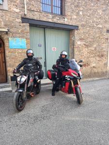 two people on motorcycles parked in front of a building at Chambres d'hôtes Sous L'Olivier in Trausse