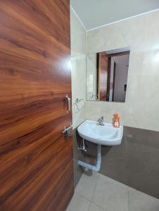 a bathroom with a sink and a wooden door at Elite Homes in Chikmagalūr