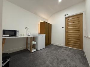 a room with a desk and a refrigerator and a door at RV Maryvale en-suite rooms in beautiful Bournville Village in Birmingham