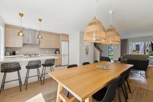 a kitchen and dining room with a wooden table and chairs at Condos Kamik Tremblant by Manitonga in Mont-Tremblant +63 photos