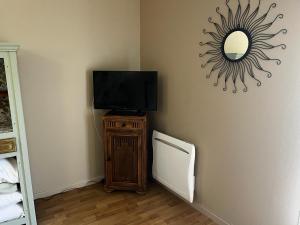a room with a television and a mirror on the wall at La maison Sainte Anne in Tour-en-Bessin