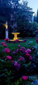 a park with a yellow fountain and pink flowers at Villa Carrara Salvadori in Grezzana