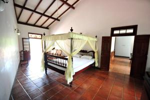 - une chambre avec un lit à baldaquin dans l'établissement Okvin River Villa, à Bentota