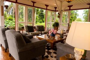 a living room with chairs and a table and windows at Hacienda El Rosario Manizales in Manizales
