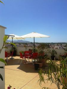 eine Terrasse mit Tischen und Sonnenschirmen auf dem Dach in der Unterkunft Hostal Palomares in Salobreña