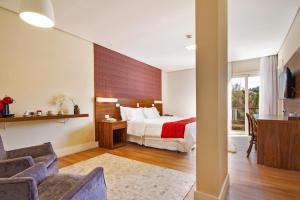 a hotel room with a bed and a desk and chairs at Hotel Chateau in Campos do Jordão +107 photos