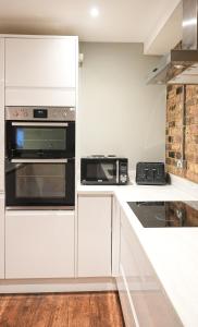 a kitchen with white cabinets and a microwave oven at Stunning Brighton Seaside 2-Bedroom Townhouse with Patio, Sleeps 6 in Brighton & Hove