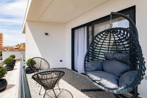 a hanging chair on a balcony with blue pillows at Austin Boutique Hotel in Sarandë