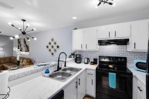 a kitchen with white cabinets and a sink at Oasis 316 - Palm Paradise in Titusville