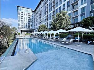 a swimming pool with chairs and umbrellas next to a building at Stunning City View Apartment Sandton City in Johannesburg