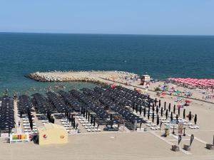 ein Strand mit Sonnenschirmen und Menschen auf Sand und Wasser in der Unterkunft Hotel Diana in Eforie Nord